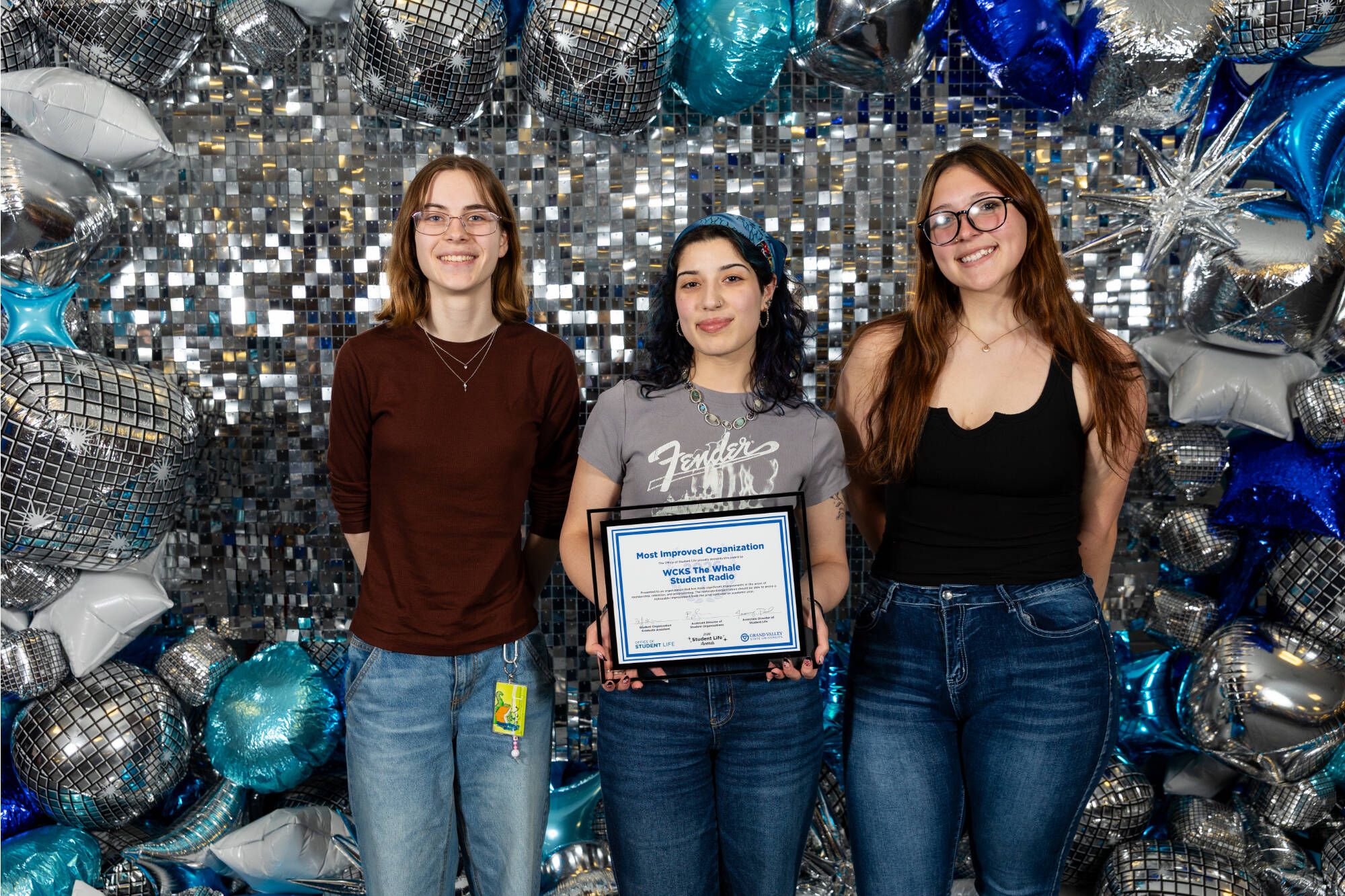 Three individuals holding an award certificate